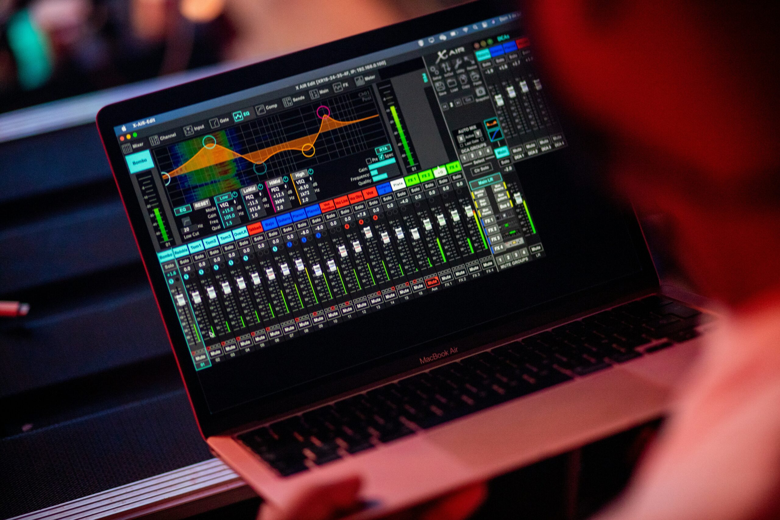 Audio mixing software displayed on a MacBook Air during a live event, showcasing a detailed equalizer and mixer controls for sound management.